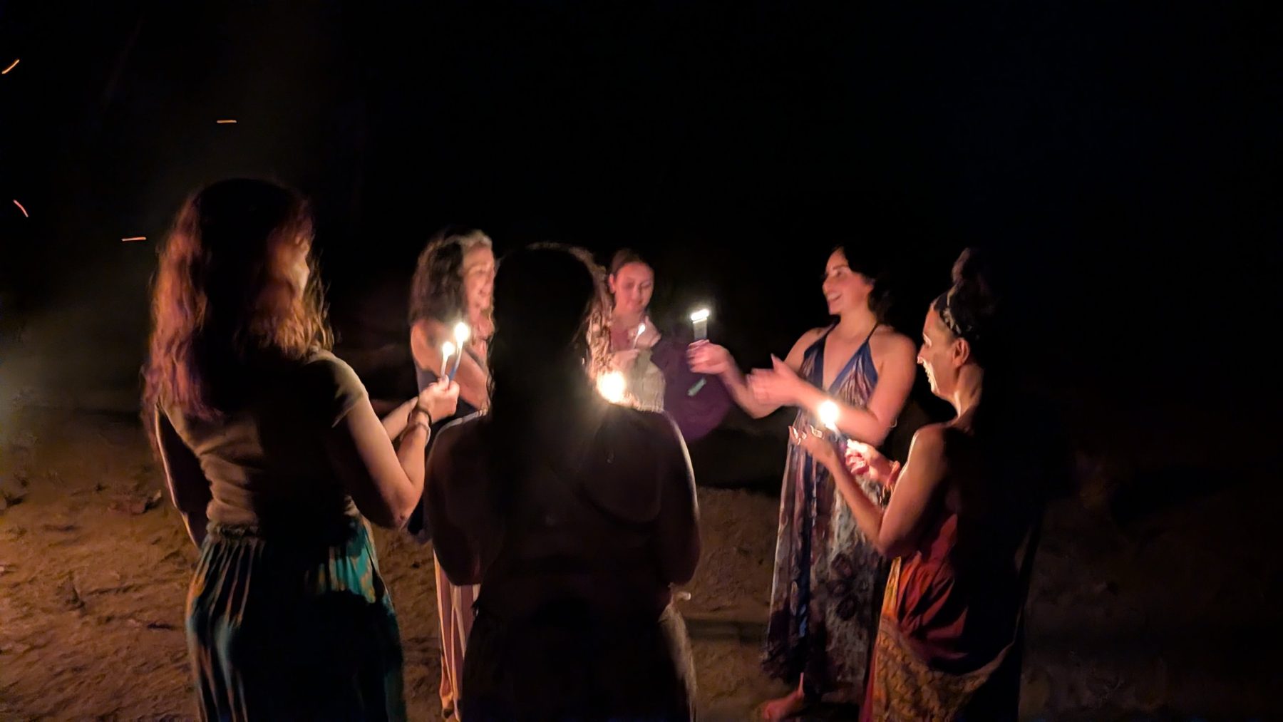 Retreat guests holding candles in a circle on the beach in Costa Rica
