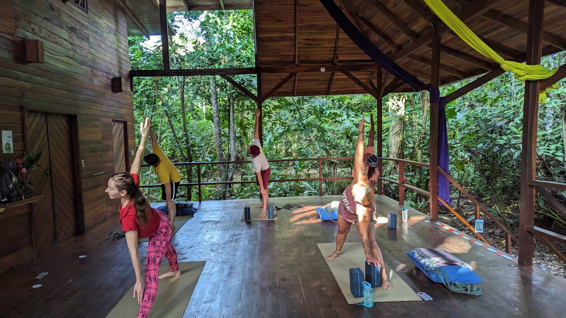 Guests practicing yoga on the open-air wooden deck surrounded by rainforest