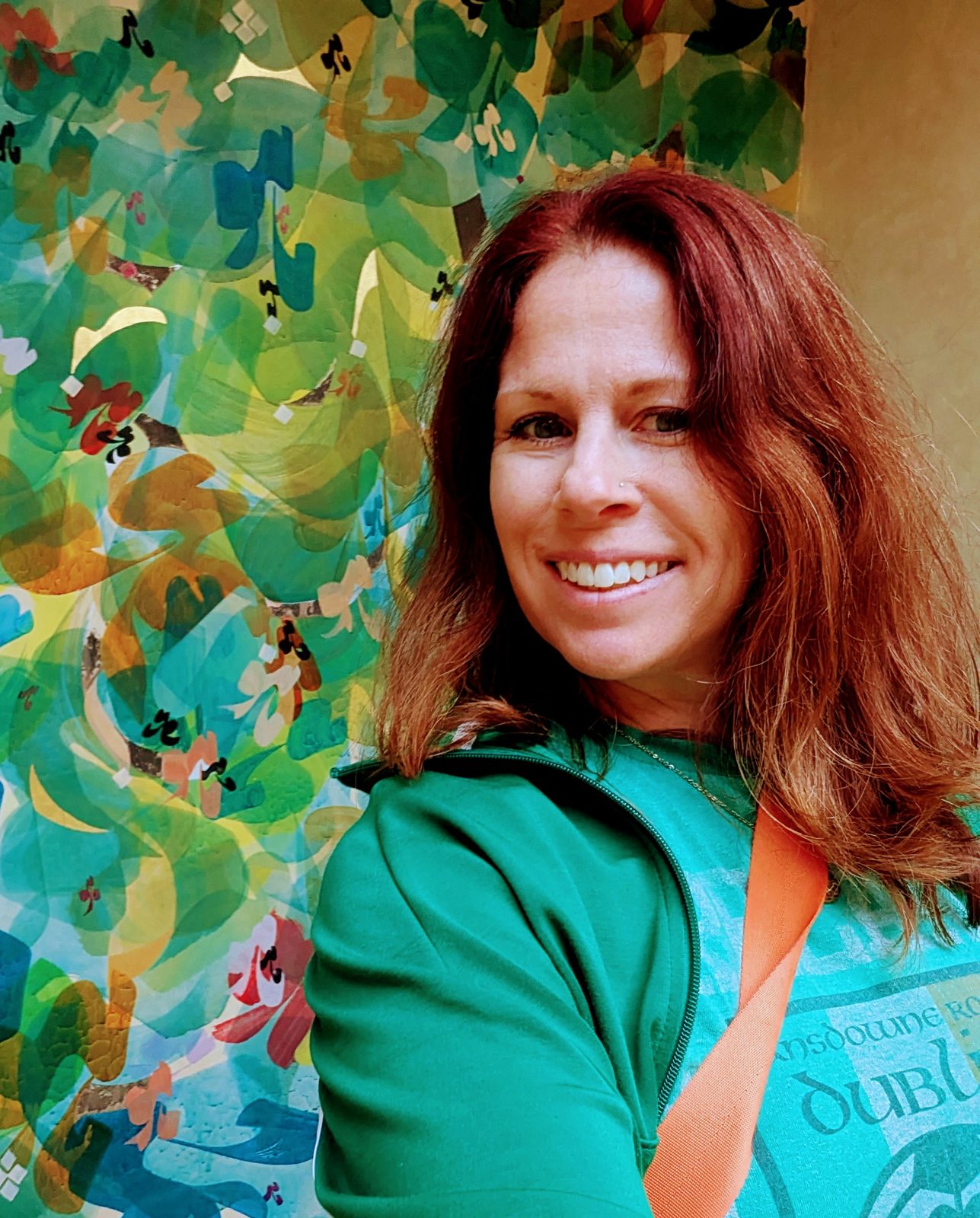 Marybeth smiling in front of a colorful painted mural